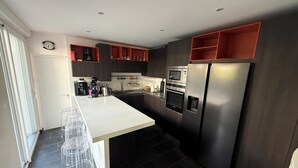 A modern kitchen with a central island, stainless steel appliances, and a clock on the wall.