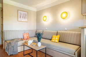 Una sala de estar moderna con un sofá, una mesa de centro, una impresión botánica enmarcada e iluminación en la pared.