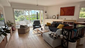 A spacious living room with a sofa, coffee table, and a bookshelf. - Marseille: sea and garden views at Endoume! (Marseille)
