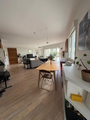 A spacious living area with a dining table, sofas, and a TV. - Marseille: sea and garden views at Endoume! (Marseille)