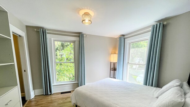A bedroom with a bed, a nightstand, a lamp, and a window with curtains. - Walk to Lake & Downtown Chelan! Room #3 (Chelan)