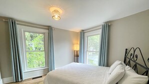 A bedroom with a large bed, two windows with curtains, a bedside lamp, and a ceiling light fixture. - Walk to Lake & Downtown Chelan! Room #3 (Chelan)