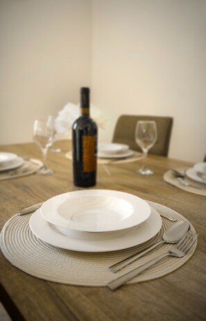 A dining table set with plates, cutlery, and a bottle of wine. - Charming 2BR Apartment with Balcony in Valletta Old Town (Valletta)