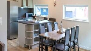 A modern kitchen with a central island, dining table, and chairs. - Ferienhaus mit Whirlpool und Sauna in Bad Bevensen (Bad Bevensen)