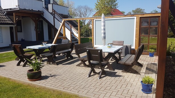 An outdoor patio with a table and chairs, a whiteboard, and a wooden pergola structure. - Vacation home Mundt Between the Bodden and the Baltic Sea, at the very top in the north of Rügen (Altenkirchen OT Drewoldke)