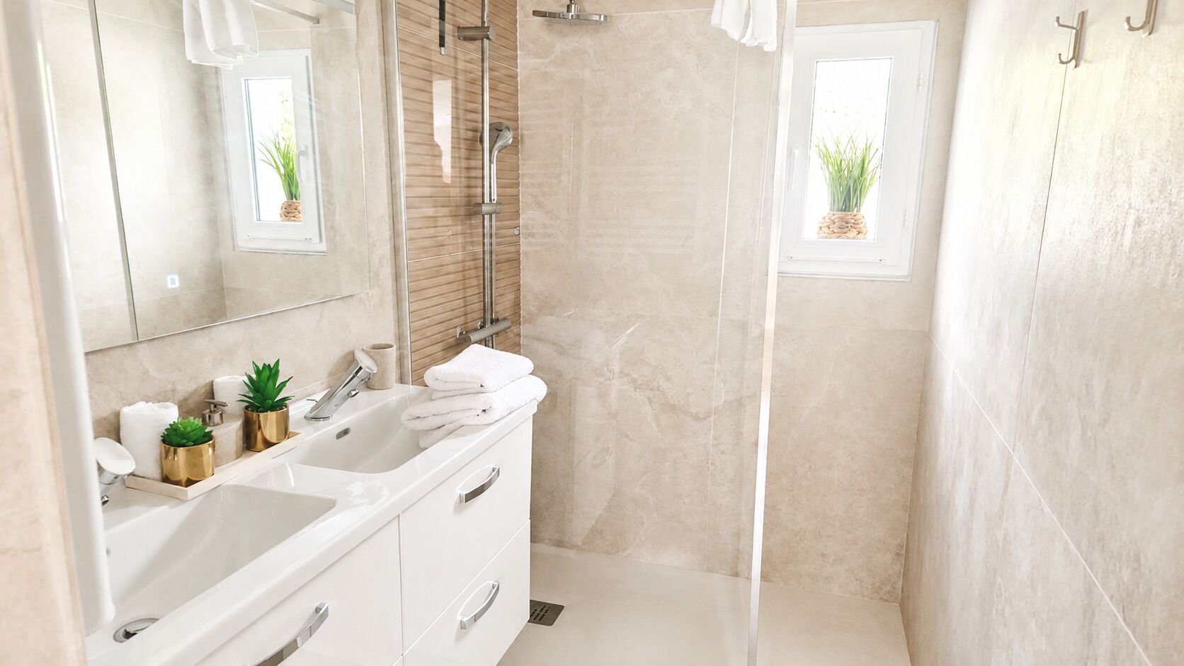 A modern bathroom with a glass-enclosed shower, a vanity with two sinks, and a large mirror.