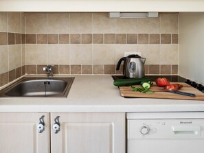 A kitchen with a sink, a kettle, a cutting board with vegetables, and a dishwasher. - 6-person Stunning Duplex Holiday House (Grospierres)