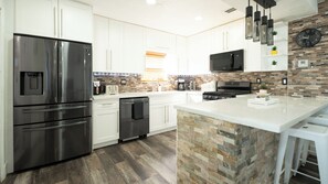 A modern kitchen with stainless steel appliances, a stone backsplash, and a large island. - FIFA World Cup 2026 · 4BR Saltwater Pool · 15 Min Hard Rock (Hollywood)