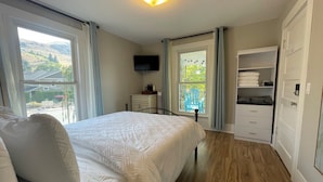 A bedroom with a bed, a TV, a dresser, a closet, and a window with a view of the outdoors. - Walk to Lake & Downtown Chelan! Room #4 (Chelan)