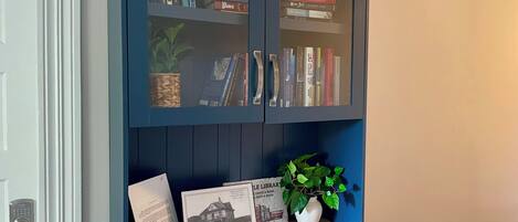 A bookshelf with books, a framed picture, a small potted plant, and a decorative item on a wooden shelf.