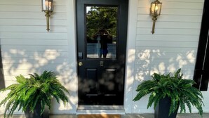 A black door with a 'hello' mat, two potted ferns, and two wall-mounted lanterns. - Walk to Lake & Downtown Chelan! Room #4 (Chelan)