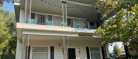 Ein zweistöckiges Gebäude mit Balkon, Eingangstür und einer Straßenschild.