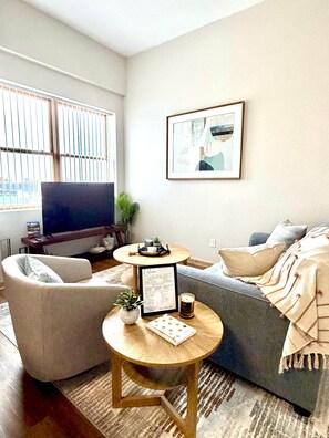 Ein Wohnzimmer mit einer Couch, einem Couchtisch, einem Fernseher und einem begrüßungsschild im Bilderrahmen.