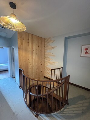 A spiral staircase with a wooden railing, a wooden wall panel, and a hanging light fixture. - La Comtoise du Barry, medieval center of Sarlat. (Sarlat-la-Canéda)