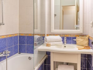 Une salle de bain Ă©quipĂ©e dâune baignoire, dâun lavabo, dâun miroir et dâun espace douche.