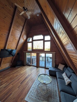 A cozy attic room with a sloped ceiling, a fireplace, a sofa, and a large window.
