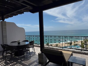Un espacio de estar al aire libre cubierto con vista al océano y la playa.