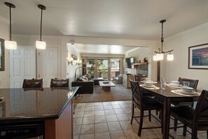 A spacious kitchen with a central island, dining area with chairs, and a living room with a sofa and chairs. - Charming Alpine Getaway at St. Anton 661 (Mammoth Lakes)