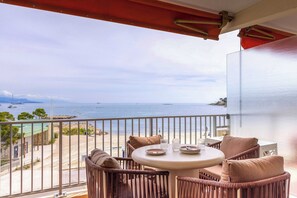 A balcony with wicker furniture, a round table, and a view of the sea and beach. - 1bdr/4p Flat With Stunning sea Views (Antibes)