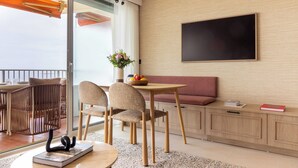 A modern room with a dining table, chairs, a sofa, a flat-screen TV, and a sliding glass door to the outside. - 1bdr/4p Flat With Stunning sea Views (Antibes)