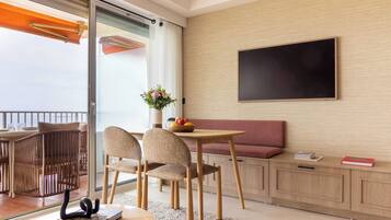 A modern room with a dining table, chairs, a sofa, a flat-screen TV, and a sliding glass door to the outside.