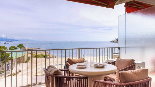 A balcony with wicker furniture, a round table, and a view of the sea. - 1bdr/4p Flat With Stunning sea Views (Antibes)