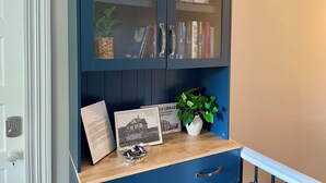A blue bookcase with glass doors, a small white vase with a plant, and a framed picture on a wooden shelf. - Walk to Lake & Downtown Chelan! Room #5 (Chelan)