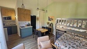 A compact room with a kitchenette, a dining area, and a bed with a floral bedspread. - Relaxation area with private Jacuzzi in the Vendée ✨️ (Le Girouard)