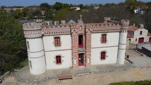 A historic building with a central tower, arched windows, and a red door. - Relaxation area with private Jacuzzi in the Vendée ✨️ (Le Girouard)