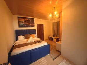 A bedroom with a bed, a nightstand, a mirror, and a cityscape painting on the wall.