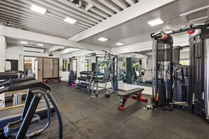 Ein Fitnessstudio mit Laufbändern, Krafttrainingsgeräten und Kurzhanteln.
