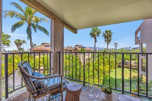 A balcony with wicker furniture, a small table, and a potted plant. - KS4301 Partial Ocean Views, Two King Bedrooms, & Prime Kihei Location (Kihei)