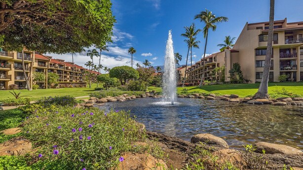 A hotel with a central fountain, surrounded by lush greenery and palm trees. - KS4301 Partial Ocean Views, Two King Bedrooms, & Prime Kihei Location (Kihei)