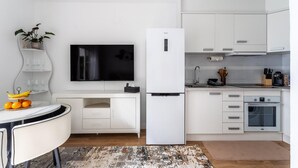 A modern kitchen with white cabinetry, a built-in oven, and a flat-screen TV. - Family-friendly Calpe Home With Pool (Calpe)