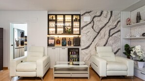 A modern living room with two white leather armchairs, a glass coffee table, a marble-patterned wall, and a built-in liquor cabinet. - Family-friendly Calpe Home With Pool (Calpe)