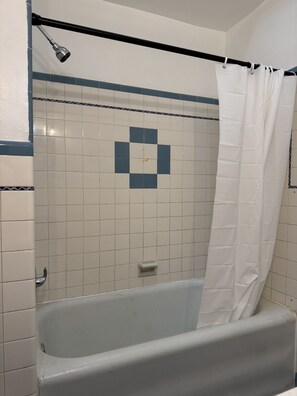 Une salle de bain avec une baignoire, un rideau de douche et un mur recouvert de carreaux formant un motif géométrique.