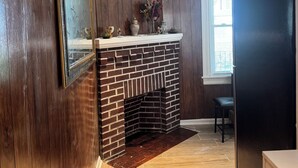 Una cocina con paneles de madera, una chimenea de ladrillo y un ventanal con persianas.
