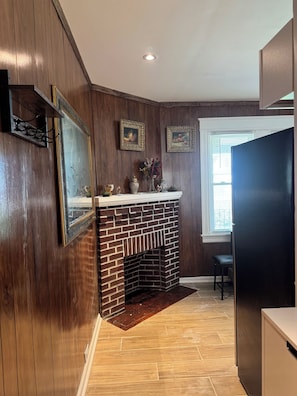 Una cocina con paneles de madera, una chimenea de ladrillo y un ventanal con persianas.