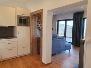 Eine moderne Küche mit integriertem Mikrowellenherd, Holztür und weißen Schränken.