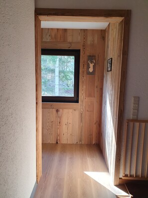 Ein Holzinnenraum mit Fenster, Holztür und einem an der Wand befestigten Hirschschädel-Dekoration.