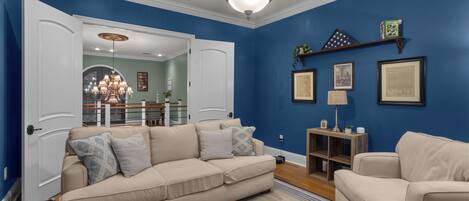 Una sala de estar con un sofá color beige, una mesa de centro y una pared azul de acento.