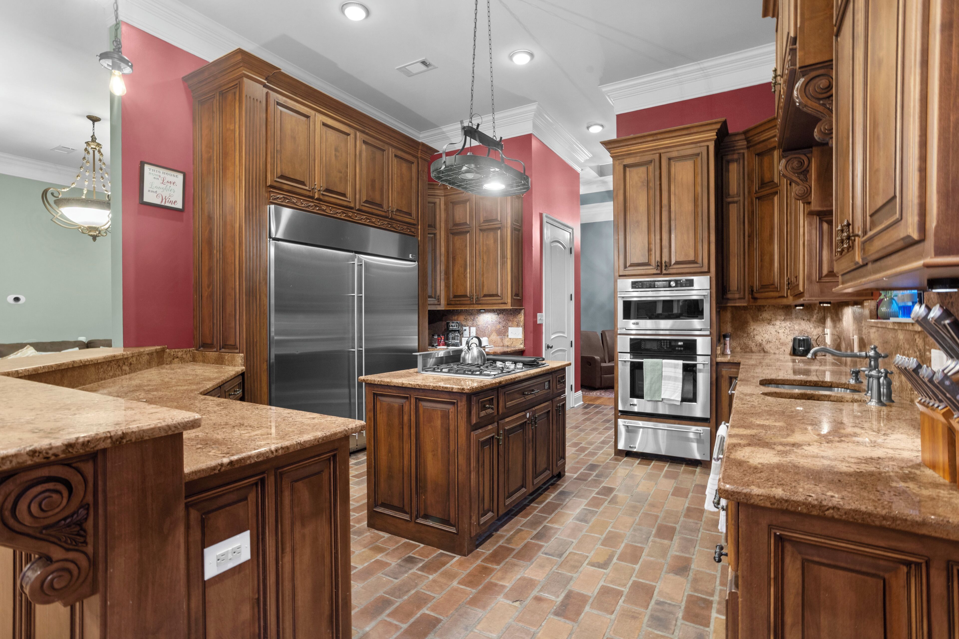 A kitchen with wooden cabinets, a stainless steel refrigerator, an oven, and a granite countertop.