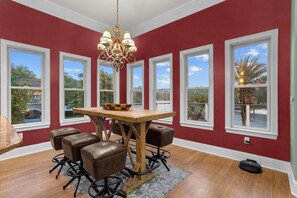 Ein Essbereich mit Holztisch, Ledersesseln, einer Chandelier und großen Fenstern.