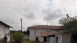 Ein Wohnhaus mit überdachter Terrasse, ein weißes Haus mit rotem Ziegeldach und einem kleinen Garten.