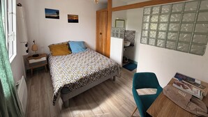 Ein Schlafzimmer mit Bett, Nachttisch, Lampe, Kommode, Stuhl und einem Fenster mit Blick.