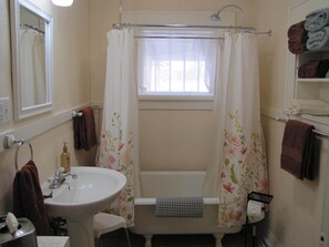 Un baño con lavamanos, espejo, cortina de ducha y toallas.