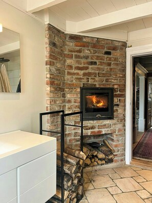 A fireplace with a stone wall, a white cabinet, and a wooden floor.