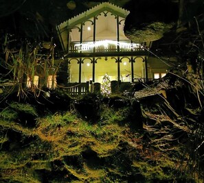 A gazebo-like structure with a roof and railing, surrounded by vegetation.