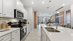Une cuisine moderne avec des meubles blancs, un four à micro-ondes et un grand îlot central doté d’un évier.