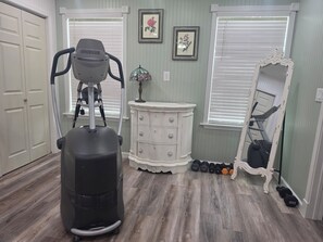 A home gym with a stationary bike, dumbbells, and a mirror.